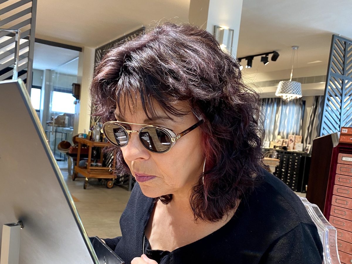 טל, סטייליסטית באופטיטופ, מודדת משקפי שמש מול המראה בחנות בחיפה